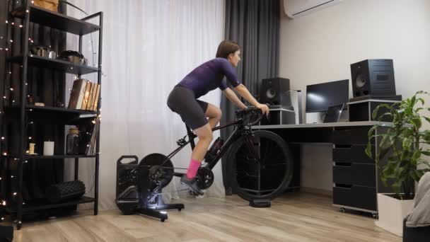 Mulher está pedalando no treinador inteligente em casa. Ciclismo Indoor — Vídeo de Stock