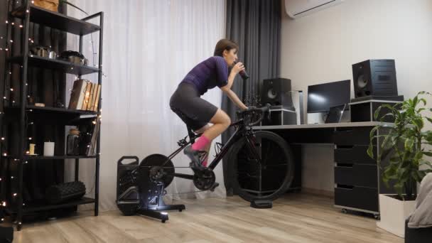 Mulher está treinando em bicicleta estática. Exercício interno. Ciclismo indoor — Vídeo de Stock