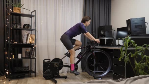 여자가 실내에서 자전거를 타고 스마트 자전거 트레이너로 심장과 건강 운동을 하고 있습니다 — 비디오