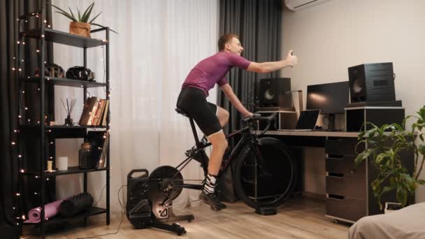사람 자전거는 정지 된 자전거를 타고 스마트폰으로 셀카를 하고 있습니다. 실내 자전거타기 — 비디오