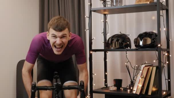 Jeune cycliste termine les courses cyclistes en ligne, sprinter hors de selle sur vélo d'exercice — Video