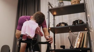 Adam durağan bisiklette çalıştıktan sonra terini havluyla siliyor.