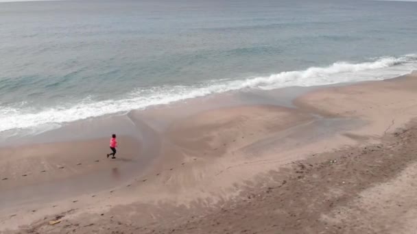 強い若い女性が嵐のビーチで走っている。女性はカーディオトレーニングを練習しています — ストック動画