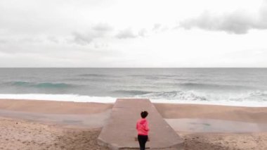 Kadın rıhtımın kenarına koşar ve büyüleyici deniz manzarasına hayran kalır.