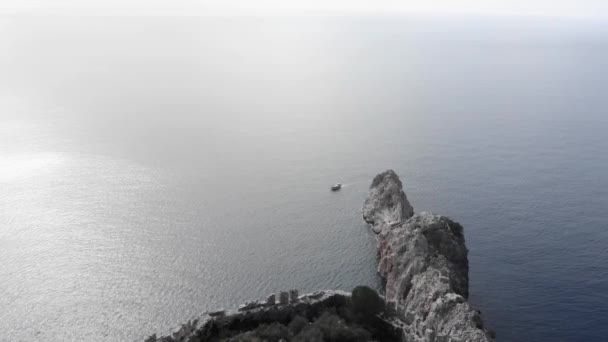 Riesige steinige Klippe im blauen Ozean. Vogelperspektive auf ruhiges Meer mit leerem Steinfelsen — Stockvideo