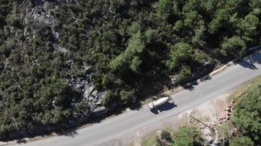 Kamyon dağlardaki boş araba yolunda ilerliyor, üst hava manzaralı.