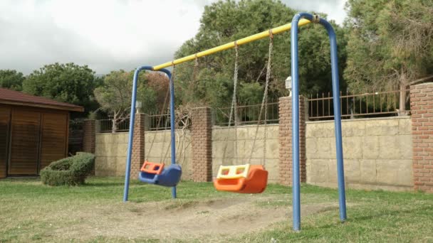 Le altalene vuote del bambino stanno oscillando nel vento al giardino dei bambini. Parco giochi vuoto durante il coronavirus — Video Stock