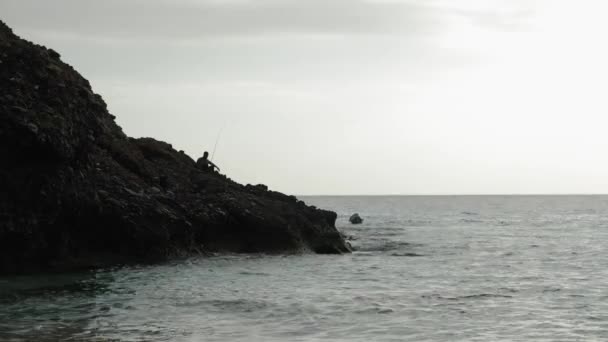 海の崖の端に魚を捕まえる漁師のシルエット — ストック動画