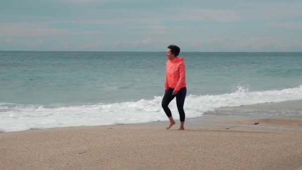 Mujer despreocupada camina en la playa vacía contra el mar tormentoso con olas gigantes — Vídeos de Stock