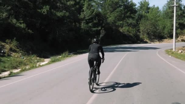 Молодая спортсменка ездит на велосипеде по лесной дороге. Профессиональный велогонщик на открытом воздухе — стоковое видео