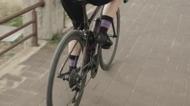 Жінка-велосипедистка педалює на шосейному велосипеді на велосипедному шляху. Велосипедне колесо, передача та касета — стокове відео