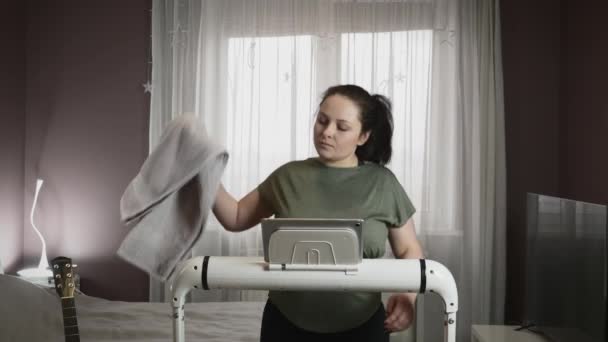 Female is wiping sweat with towel during fitness cardio exercises on treadmill at home — Stock Video