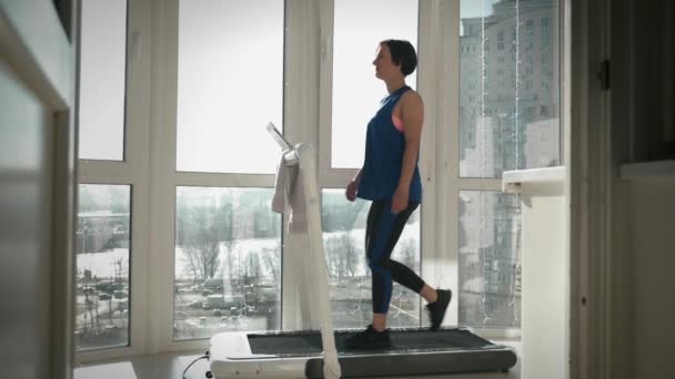 Wanita berjalan di atas mesin berjalan di rumah. Fitness di rumah. Gaya hidup sehat — Stok Video