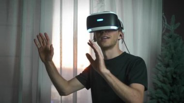 Sanal gerçeklik kulaklığı kullanan, geliştirilmiş gerçeklikte çalışan ve el kol hareketi yapan adam.