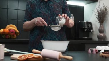 Kadın un eleme yapıyor. Kadın evde yemek pişiriyor. Kadın mutfakta yemek pişiriyor.