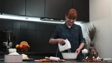 Kadın hamuru el elektrikli mikserle karıştırıyor. Pasta hamuru yapan kadın