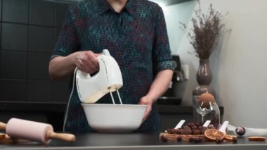 Kadın elektrikli el mikseriyle yumurta çırpıyor. Krema yapma süreci