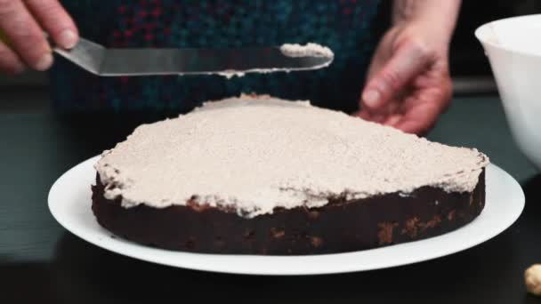 Vrouw giet room op spons cake met behulp van gebak spatel. Crèmecake met boterroom — Stockvideo