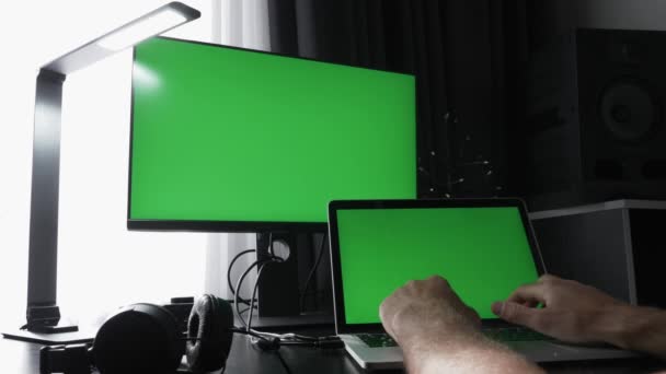 Mężczyzna programista pracujący na laptopie z dwa monitory z chroma klucz zielone ekrany — Wideo stockowe