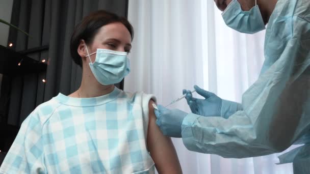 Молода жінка отримує вакцинацію від коронавірусу від лікаря в клініці — стокове відео