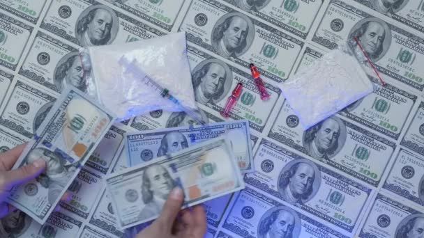 Пересчитывать деньги на фоне наркотиков, шприца и долларов. Платить деньги за наркотики — стоковое видео