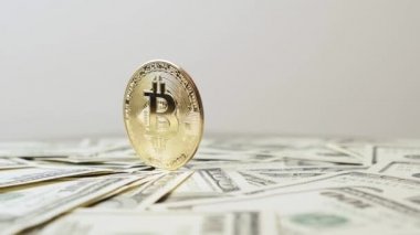 Dolar arkaplanında dönen altın bitcoin. Kripto para birimi ve dolar masada.