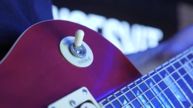 Gitarist, stüdyoda üçlü ritim seçmek için elektro gitar açma düğmesini açıyor.