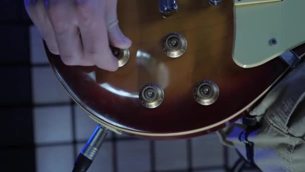 Boutons de volume et de tonalité tournant à la main. Guitariste accordant la guitare électrique au studio — Video