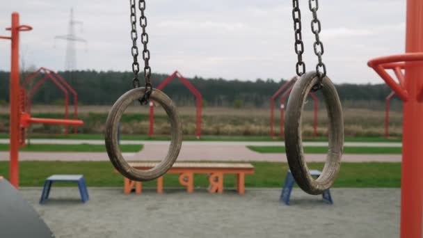 Катання на гімнастичних кільцях на дитячому майданчику. Гімнастичні кільця гойдаються повільно — стокове відео