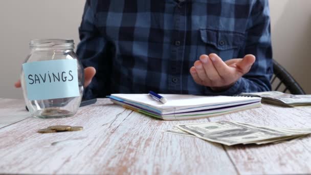 Man putting money coins into glass jar with inscription savings. Saving money — Video Stock