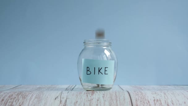 Risparmiare soldi per la bici. Lancio di monete in vaso di vetro con iscrizione bici — Video Stock