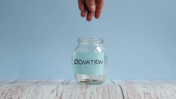 Mão jogando moedas em jarro com doação inscrição. Conceito de poupança de dinheiro — Vídeo de Stock