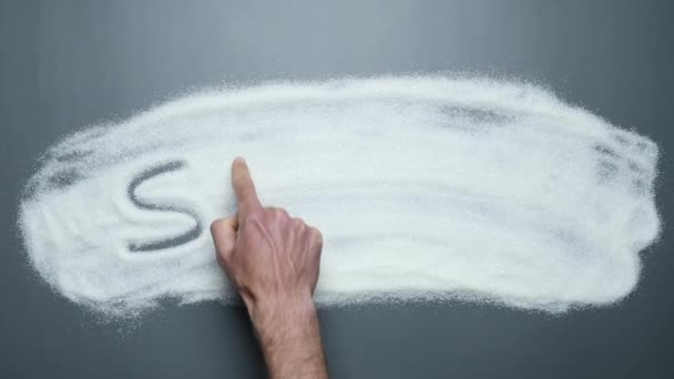 Рука писать слово сахар на фоне белого сахара. Сахар убивает. Предотвращение рака и диабета — стоковое видео