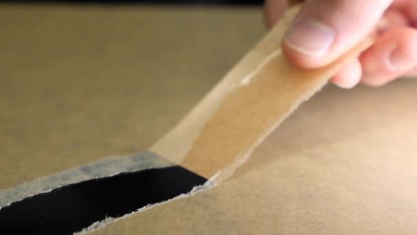 Bort med händerna från självhäftande papper. Manlig hand skalar bort tejp och packa upp rutan — Stockvideo