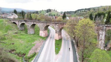 Bisikletçi bisikletiyle eski viyadük tren köprüsünden geçiyor. Bisiklet ve triatlon