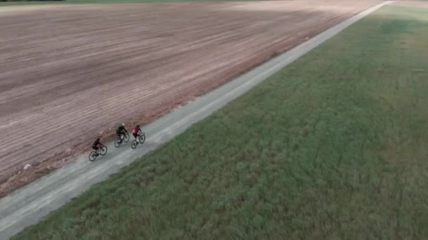 People riding on bikes on gravel road. Cyclists cycling on gravel bicycles in fields — стоковое видео
