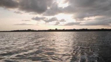 Deniz batımı. Gün batımında şehir binalarının silueti. Güneş ışığı su yüzeyine yansıyor