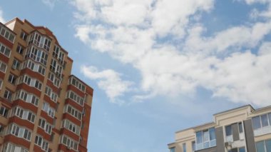 Şehrin gökdelenleri mavi bulutlu gökyüzüne karşı, zaman atlaması. Bulutlar şehrin üzerinde hareket ediyor