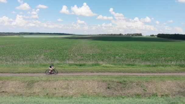 Kvinnors cykling. Ridning grus cykel. Cyklist rider cykel på grusväg på ängen — Stockvideo