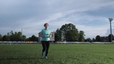 Kadın koşuyor. Yeşil çimenlerde koşan kadın, sağlıklı yaşam tarzını sürdürüyor.