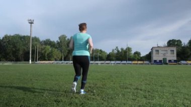 Koşmak ve koşmak. Stadyumda kardiyo egzersizi yapan bir kadın. Antrenman eğitimi