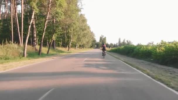 Donna ciclista in bicicletta su strada al tramonto. Allenamento professionale triatleta in bicicletta — Video Stock