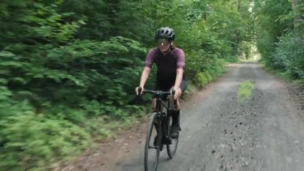 Cyclisme en gravier. Femme en vélo dans la forêt. Cycliste tourne pédales sur vélo le long de la route de gravier — Video