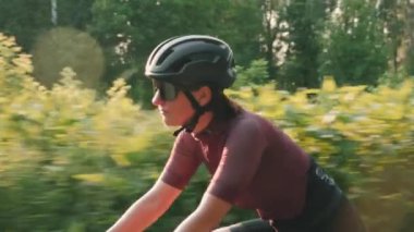 Bisiklete binen kendinden emin atletik kadın. Bisikletli gün batımında bisiklet sürüyor.