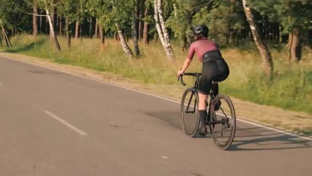 Велоспорт і тріатлон. Жінка тренується на велосипеді на заході сонця. Велосипедист їде на велосипеді на сході сонця — стокове відео
