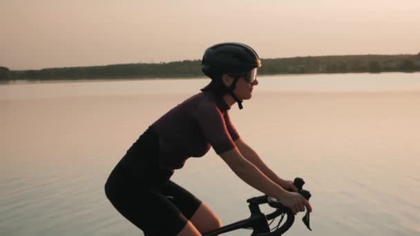 Radfahren bei Sonnenuntergang. Radfahren bei Sonnenuntergang. Fitte Frau tritt bei Sonnenschein auf Fahrrad in die Pedale — Stockvideo