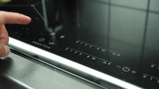 Finger presses electronic touch start button on hob. Induction stove control panel — Stock Video
