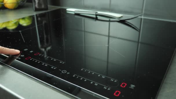 Hand turning on induction electric touch stove and putting pan on hob — Stock Video