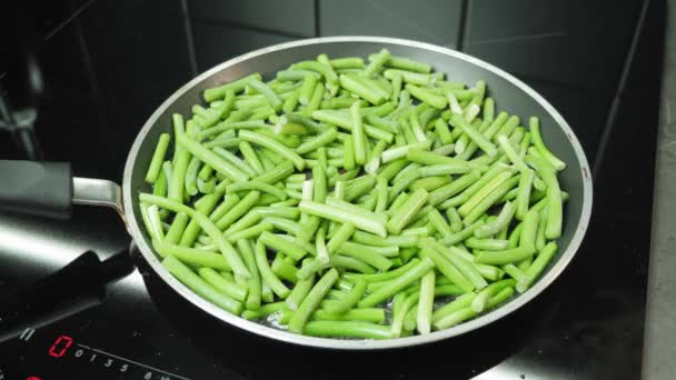 Zubereitung von grünen Bohnen in der Pfanne in der modernen Küche. Junge Knoblauchsprossen in Pfanne kochen — Stockvideo