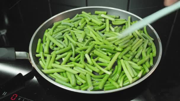 Cooking green beans in frying pan. Frying green beans with sprouts garlic on skillet pan — Stok video